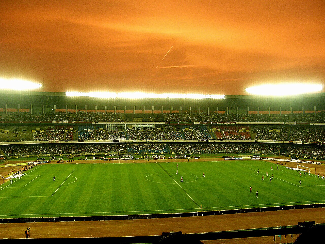 FairPlay Kolkata Football Derby: two derby players challenging for the ball in front of banners and flares